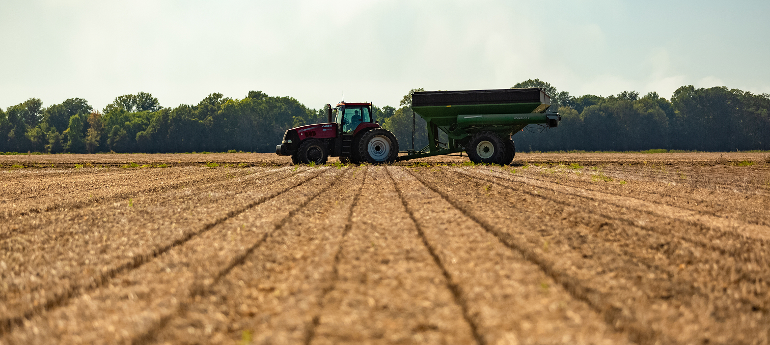 Tractor pulling grain cart across harvested field